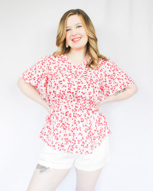 White blouse with bright pink leopard print all over pattern with flowy short sleeves, peplum top, v-neckline 