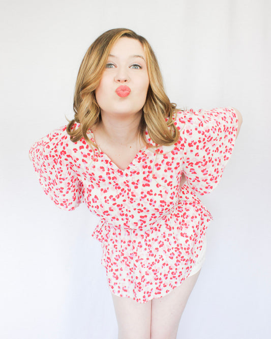 White blouse with bright pink leopard print all over pattern with flowy short sleeves, peplum top, v-neckline 