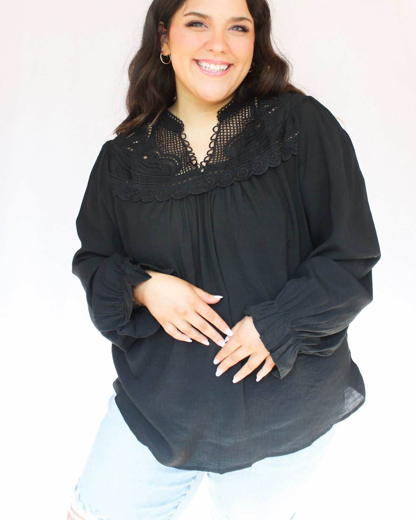 Long sleeve black top with lace detailing on the front collar and top of the blouse in a v-neckline