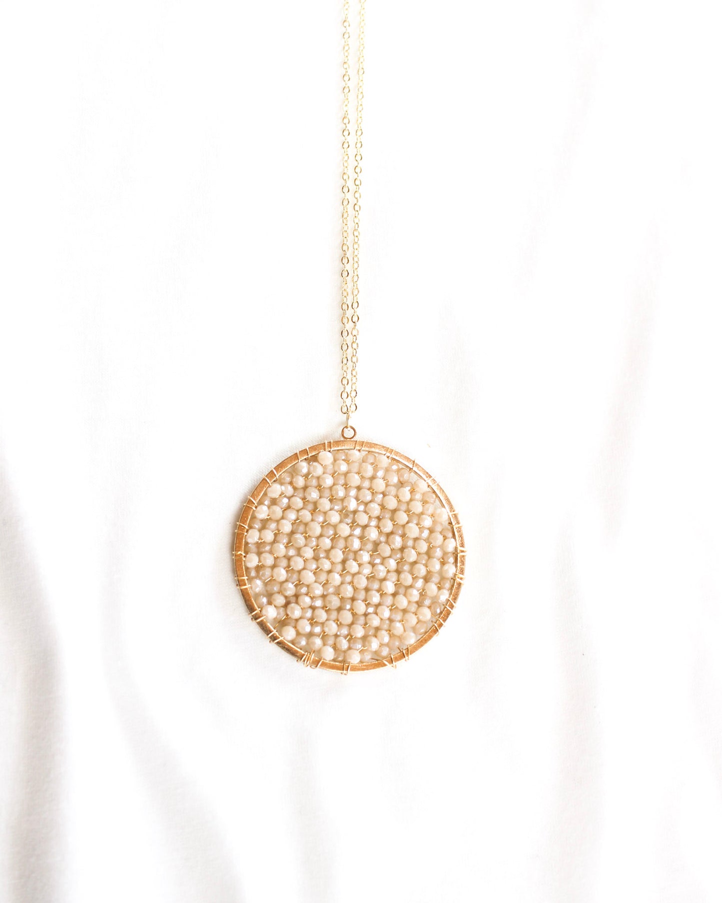 long gold chain necklace with a round brown crystalized filled circle pendant