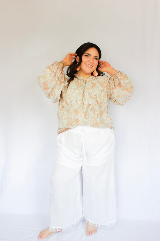 White flowy thin pants with built in shorts, drawstring waistband, two pockets, and frayed bottoms