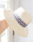 Cream white straw basket weave wide brim fedora hat with red and blue asymmetrical design strip band around 