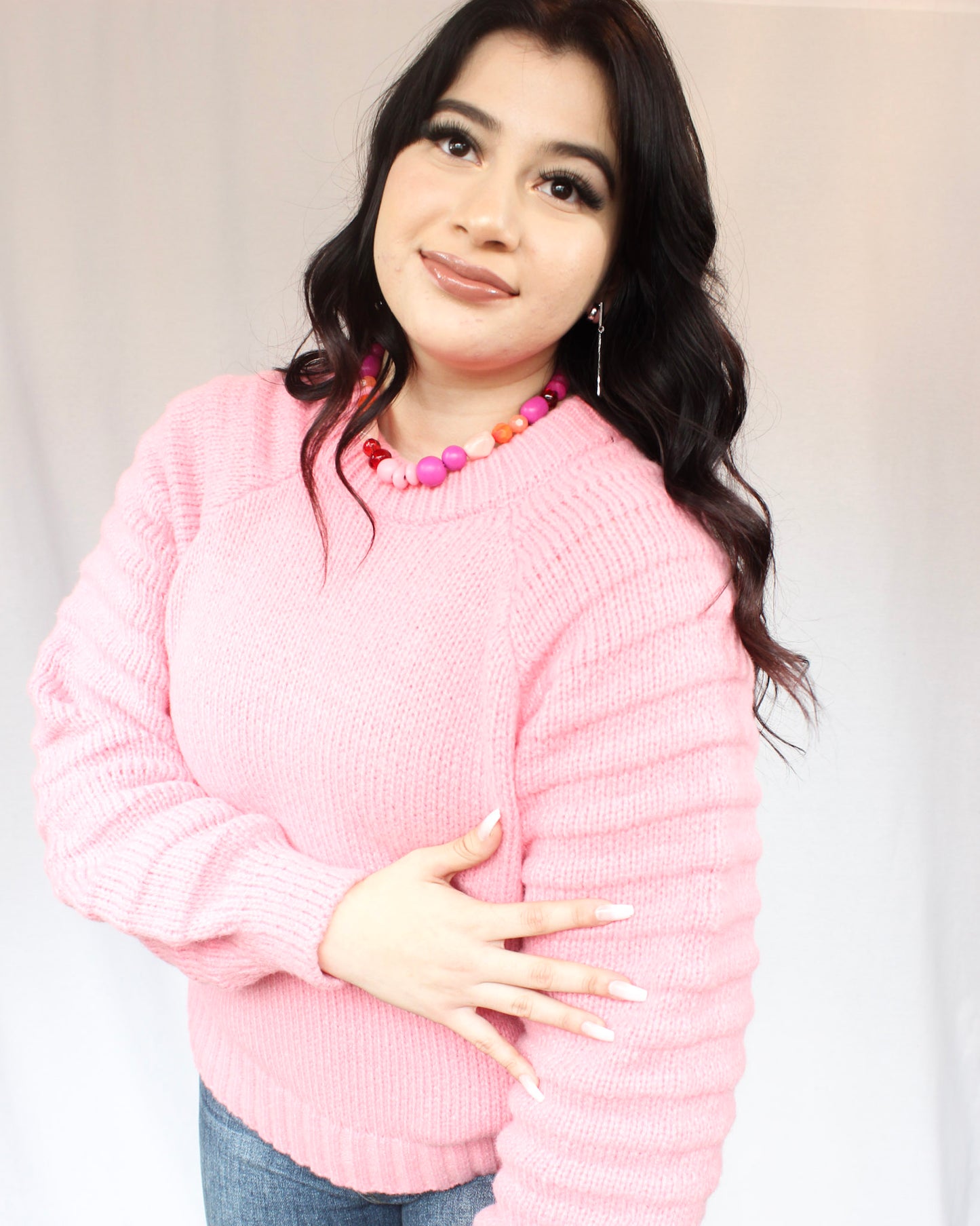 Bright pink thick sweater with ribbed hem round neck and raglan balloon sleeves paired with Judy Blue Jeans