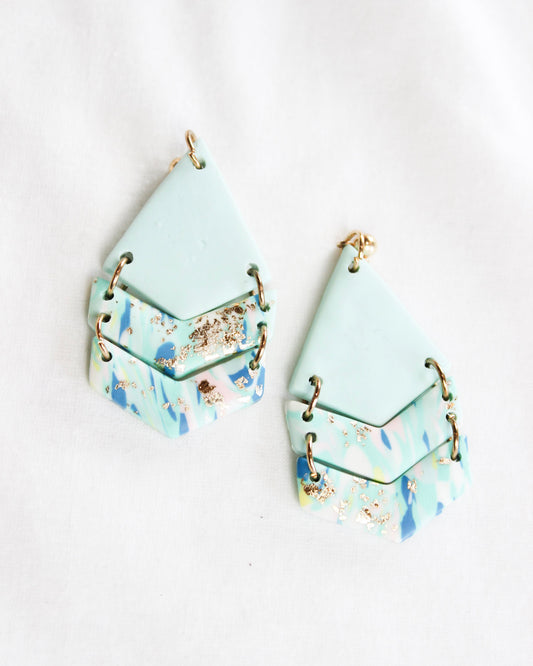 Light baby blue triangle dangle earrings with paint detail on dangles and gold accents
