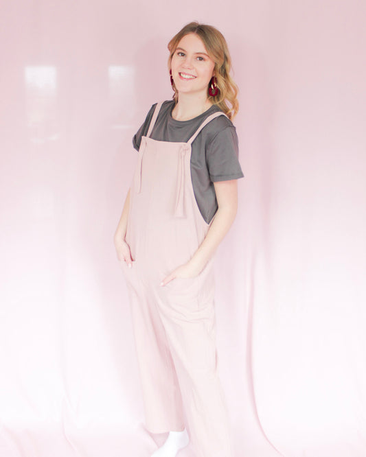 Light blush pink loose fit overalls with customizable tie straps two deep pockets on the front 