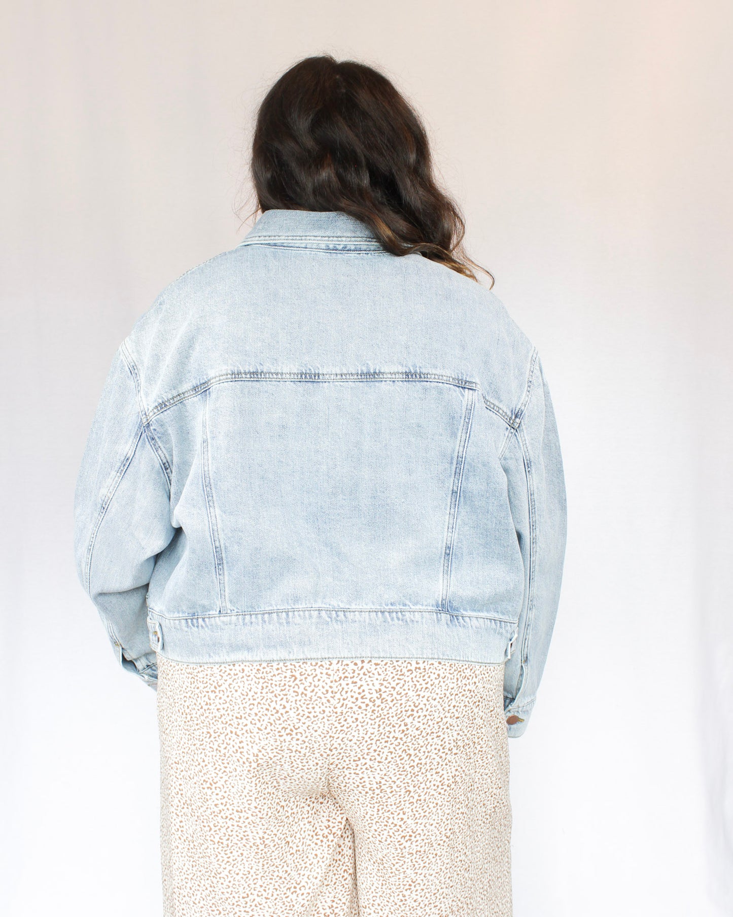 Slightly cropped light wash stretchy denim jacket with two chest pockets and two hand pockets, silver buttons