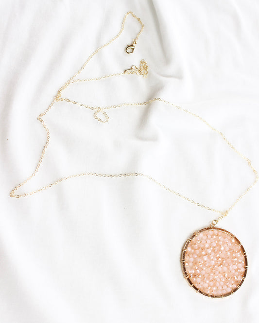 long gold chain necklace with a round pink crystalized filled circle pendant