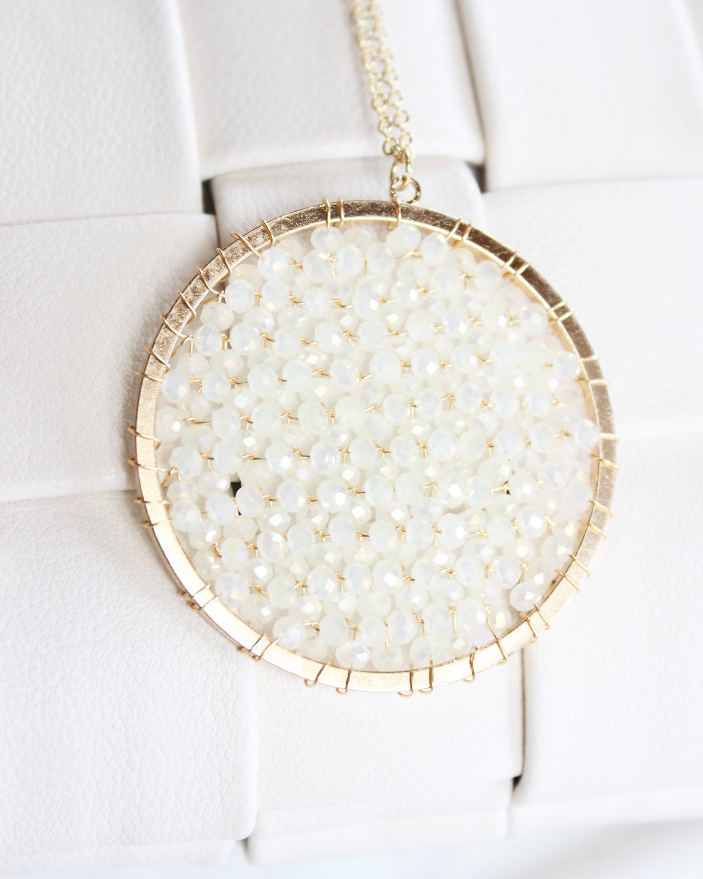 long gold chain necklace with a round white crystalized filled circle pendant