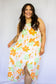 White high low dress with big floral design in bright orange, green, and pale pink adjustable spaghetti strips high round neckline