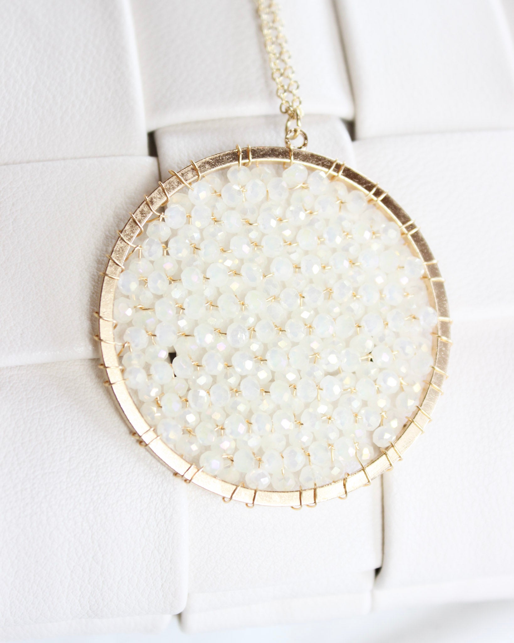 long gold chain necklace with a round white crystalized filled circle pendant